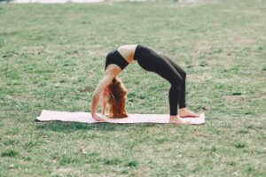 woman doing wheel yoga pose on grass